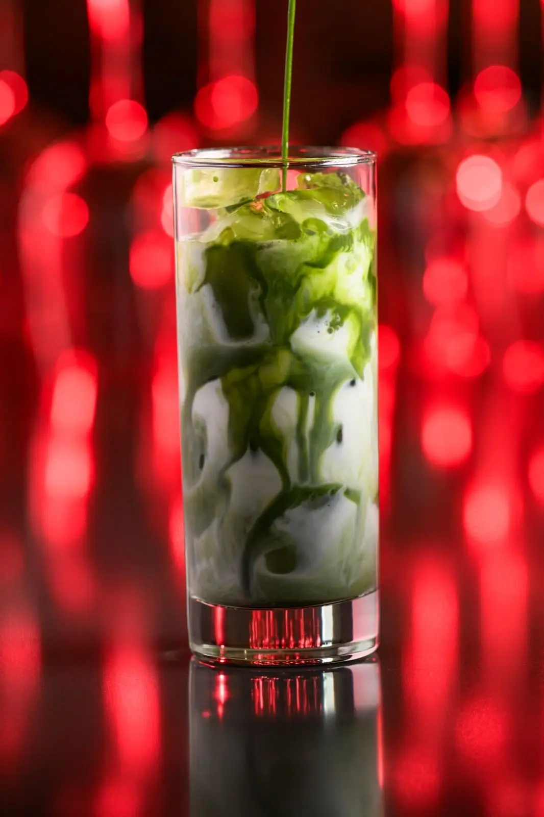Jinbeh matcha cocktail with green matcha being swirled into milk