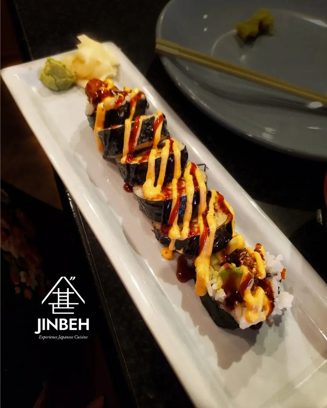 Jinbeh branded sushi plate with fresh rolls